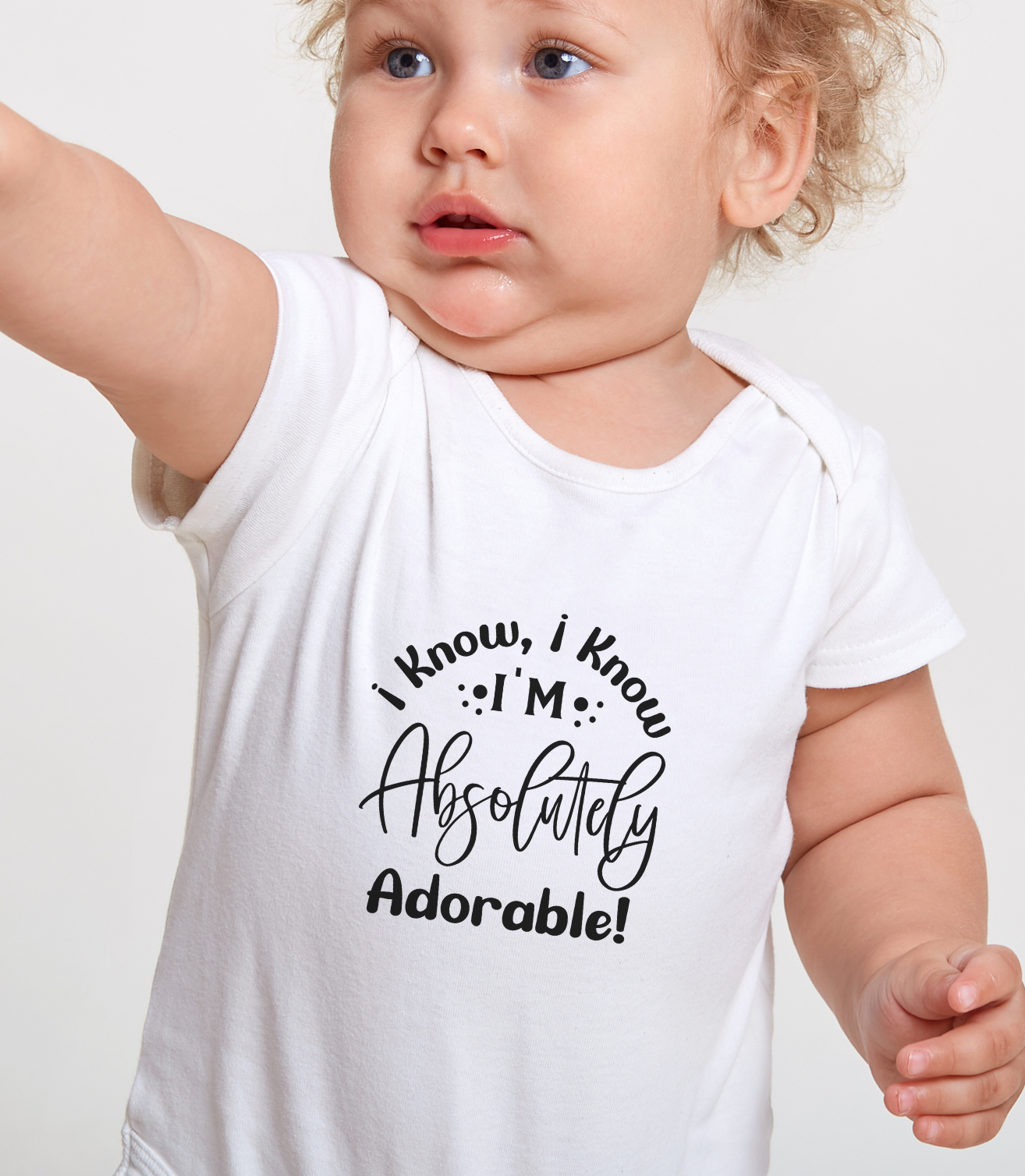 Baby wearing a white onesie with text "I know I'm absolutely adorable" on a plain background