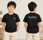 A young boy modeling a black short-sleeve t-shirt in a split front and back view. The front features a small white circular logo on the left chest, and the back features white text in Devanagari script reading 'विद्या दैत्य विनयम्' with 'Knowledge is the ultimate power' underneath.