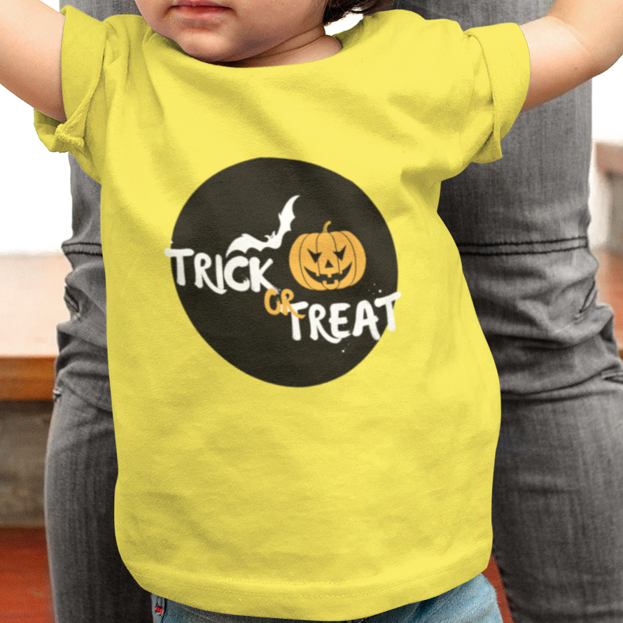 Child wearing a yellow 'Trick or Treat' shirt being held by an adult.