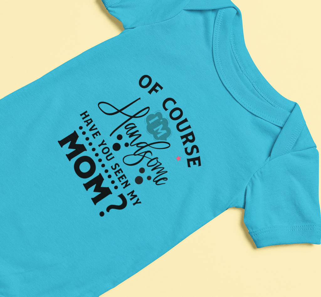 Blue baby onesie with humorous text “Of Course I’m Handsome – Have You Seen My Mom?” on a beige background