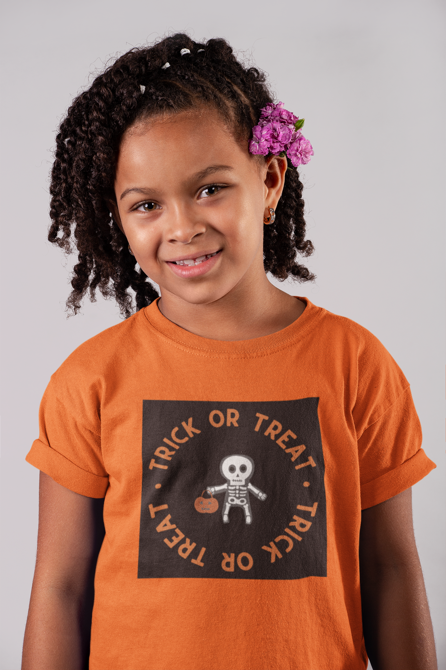 Young girl wearing an orange 'Trick or Treat' shirt with a skeleton design.